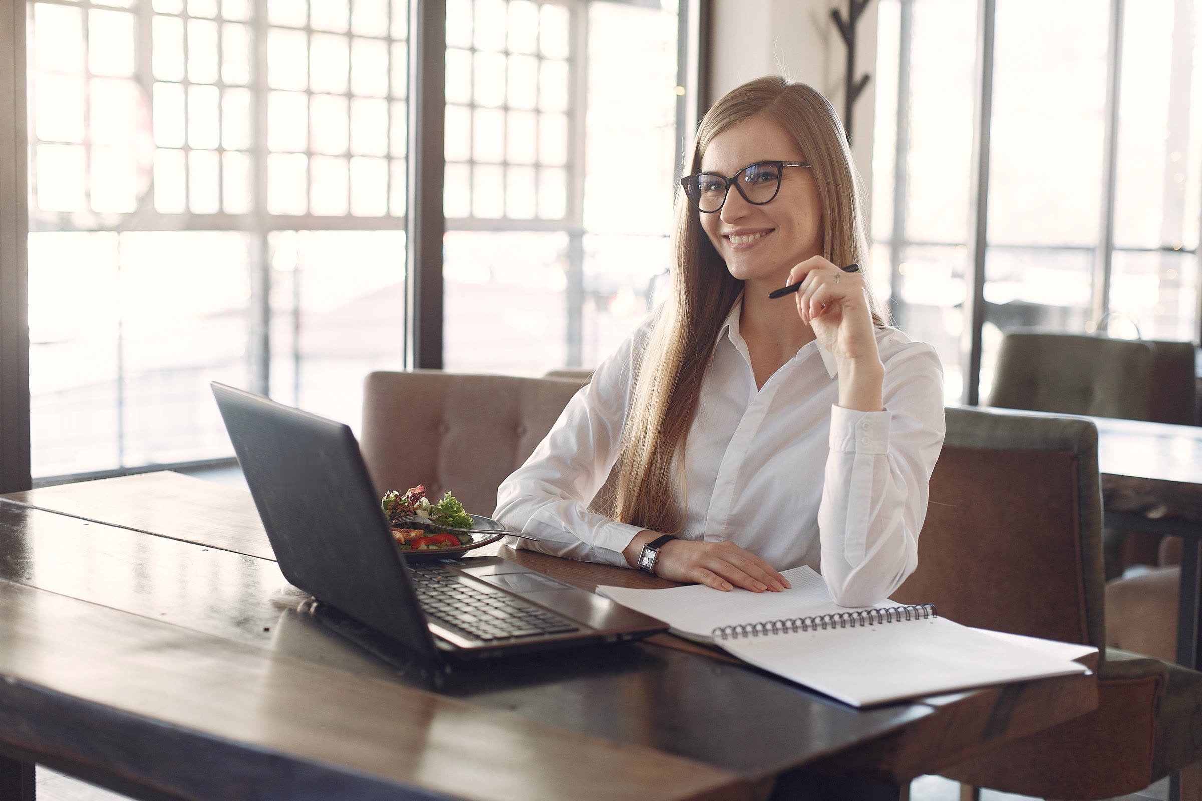 A smiling business owner with glasses at her laptop